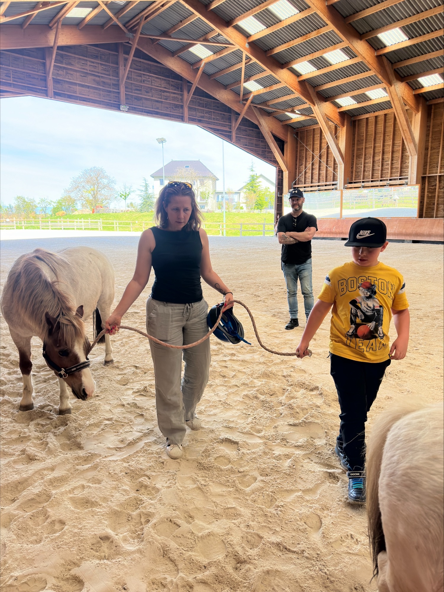 enfant accompagné de parents menant poney dans un manège